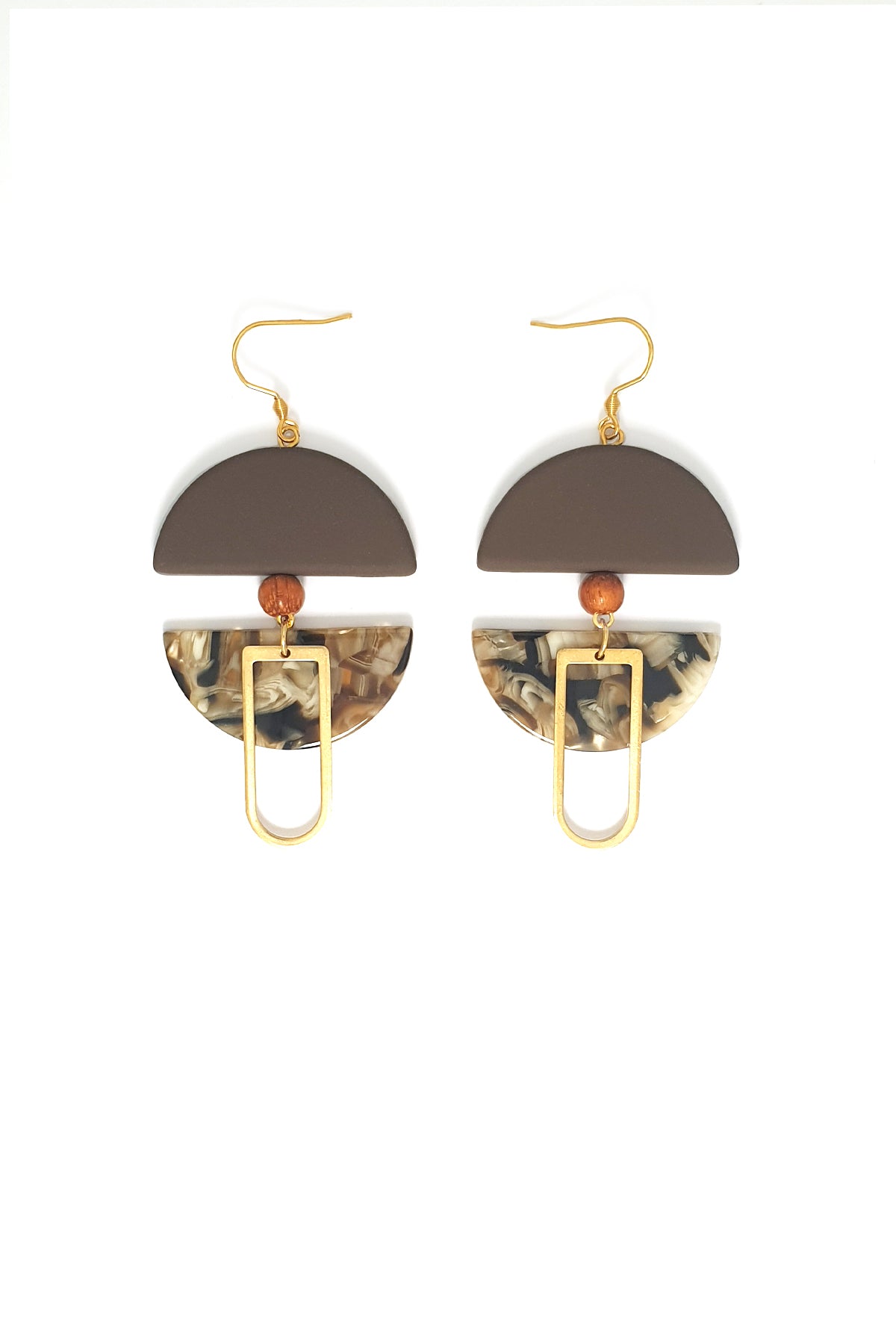 A pair of dangle earrings with a hook sit against a white background. They feature a brown arch shaped bead, a small wooden bead, a brown acrylic half circle, and an elongated D shape brass piece.