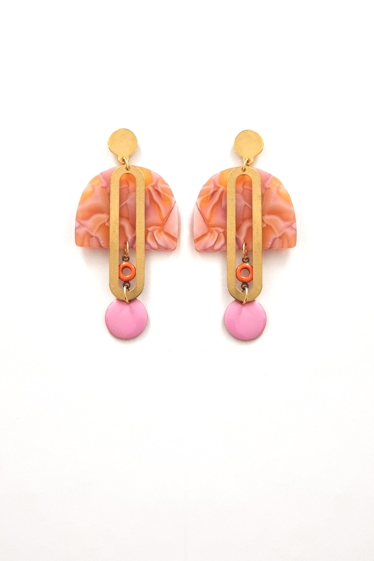 A pair of stud dangle earrings sits against a white background. They feature an orange and orchid multicoloured acrylic arch, an elongated oval brass piece with a small orange enamel connector attaching the acrylic piece to the brass, and at the bottom hangs an orchid enamel dot.