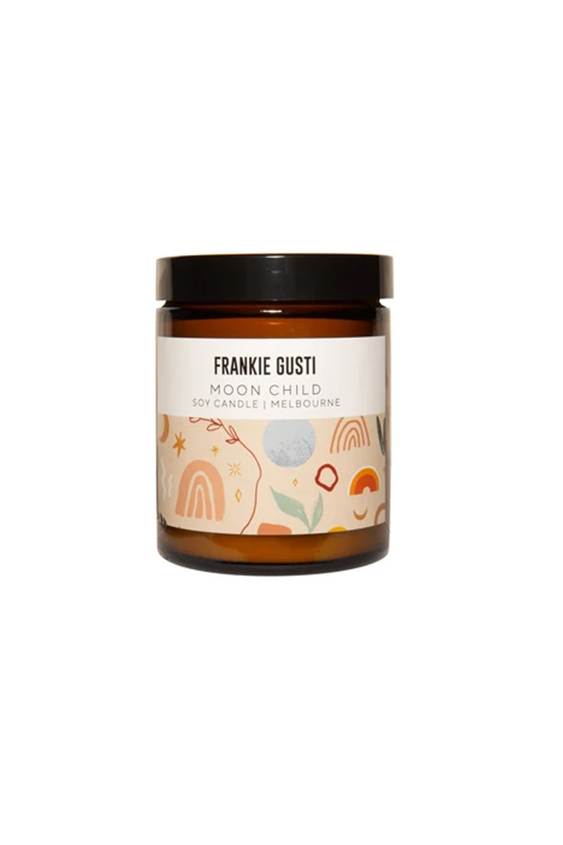 A candle jar sits against a white background. The jar is amber and has a black lid, it has a label with a cream background and abstract lines, leaves and rainbow shapes in green, peach, white and orange. It has a cream box up the top with the words FRANKIE GUSTI MOON CHILD SOY CANDLE | MELBOURE written in modern uppercase text.