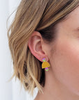 A lady with short blonde hair models a close up, side view of the Deuce studs in chartreuse.