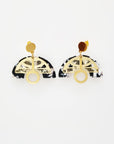 A pair of stud dangle earrings sit against a white background. They feature a black and white acrylic arch, a deco style brass arch shape, and a brass drop with and O-shape that sits perfectly in the rounded bottom of the acrylic arch.