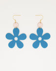 A pair of blue acrylic daisy dangle earrings with a light pink enamel dot attached to a hook. Pictured against a white background.