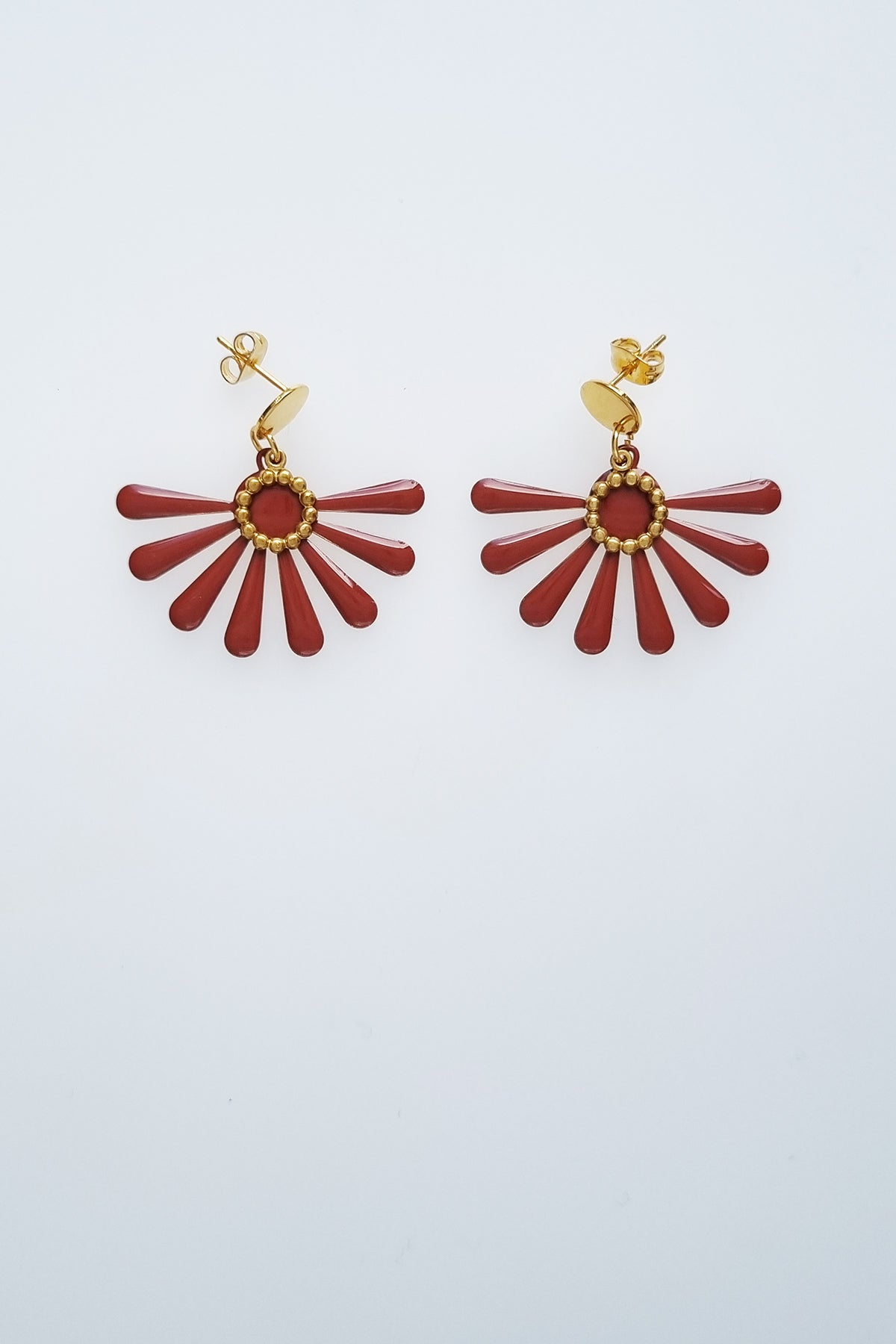 A pair of stud dangle earrings sit against a white background. They feature a chocolate coloured floral enamel shape and a tiny brass ring encircles the disk of the floral enamel piece.