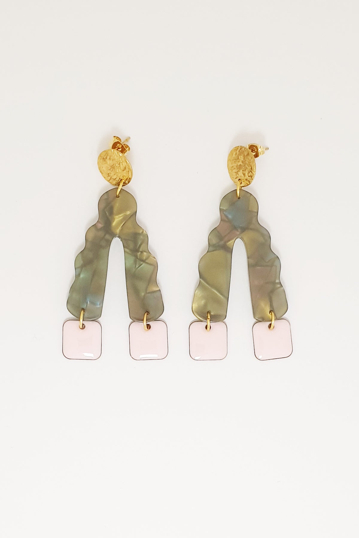 A pair of stud dangle earrings sit against a white background. They feature a textured circular gold stud top, a green wavy upside down V-shaped acrylic, and blossom pink square shaped enamel drops hanging from each end of the acrylic.