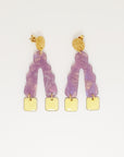 A pair of stud dangle earrings sit against a white background. They feature a textured circular gold stud top, a purple wavy upside down V-shaped acrylic, and lemon yellow square shaped enamel drops hanging from each end of the acrylic.  