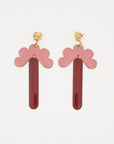 A pair of stud dangle earrings lay against a white background. They feature a gold flower shaped stud top, a pink enamel connector piece with resemblance to a half flower, and a coffee enamel drop.