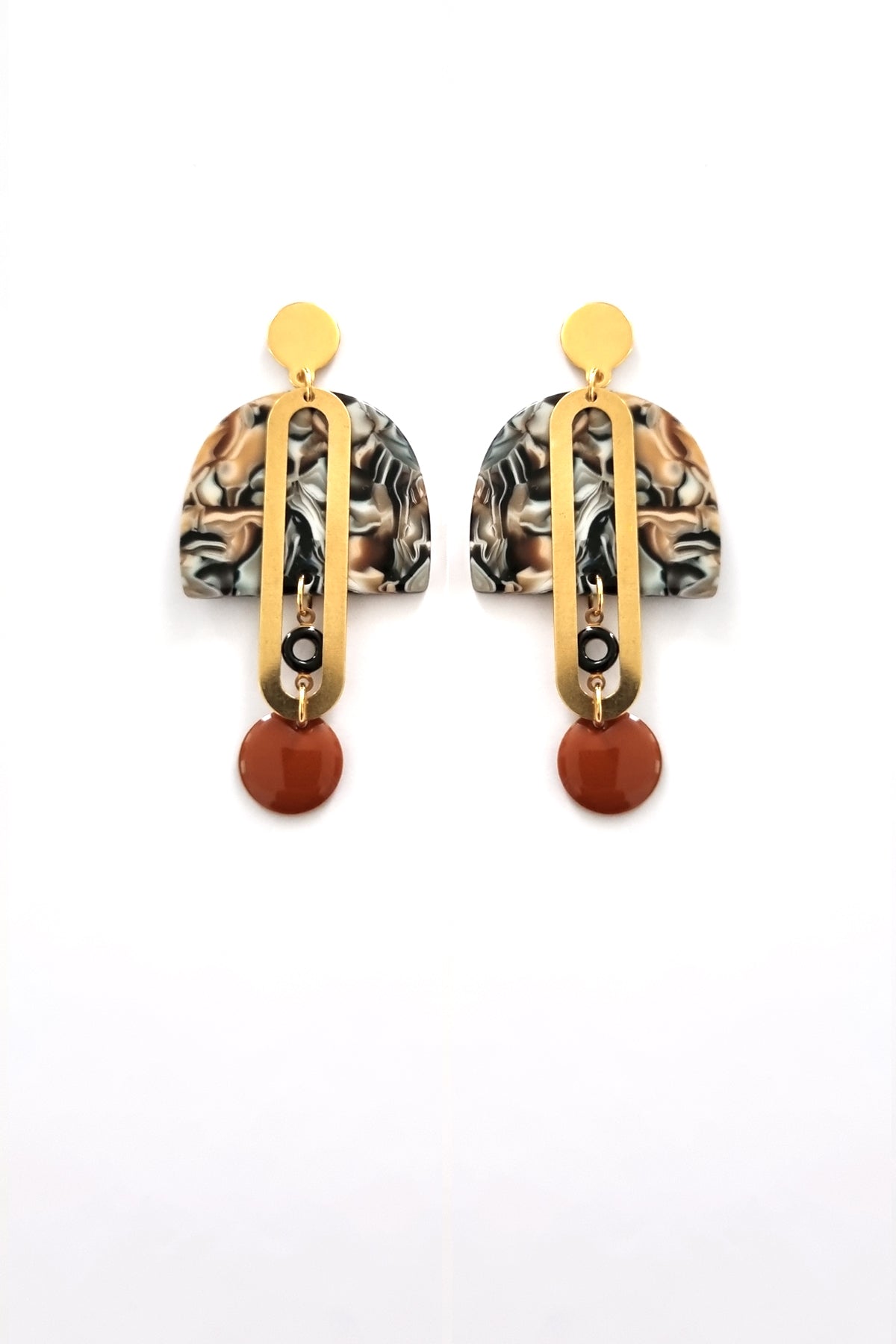 A pair of stud dangle earrings sits against a white background. They feature a brown multicoloured acrylic arch, an elongated oval brass piece with a small black enamel connector attaching the acrylic  piece to the brass, and  at the bottom hangs a brown enamel dot.   