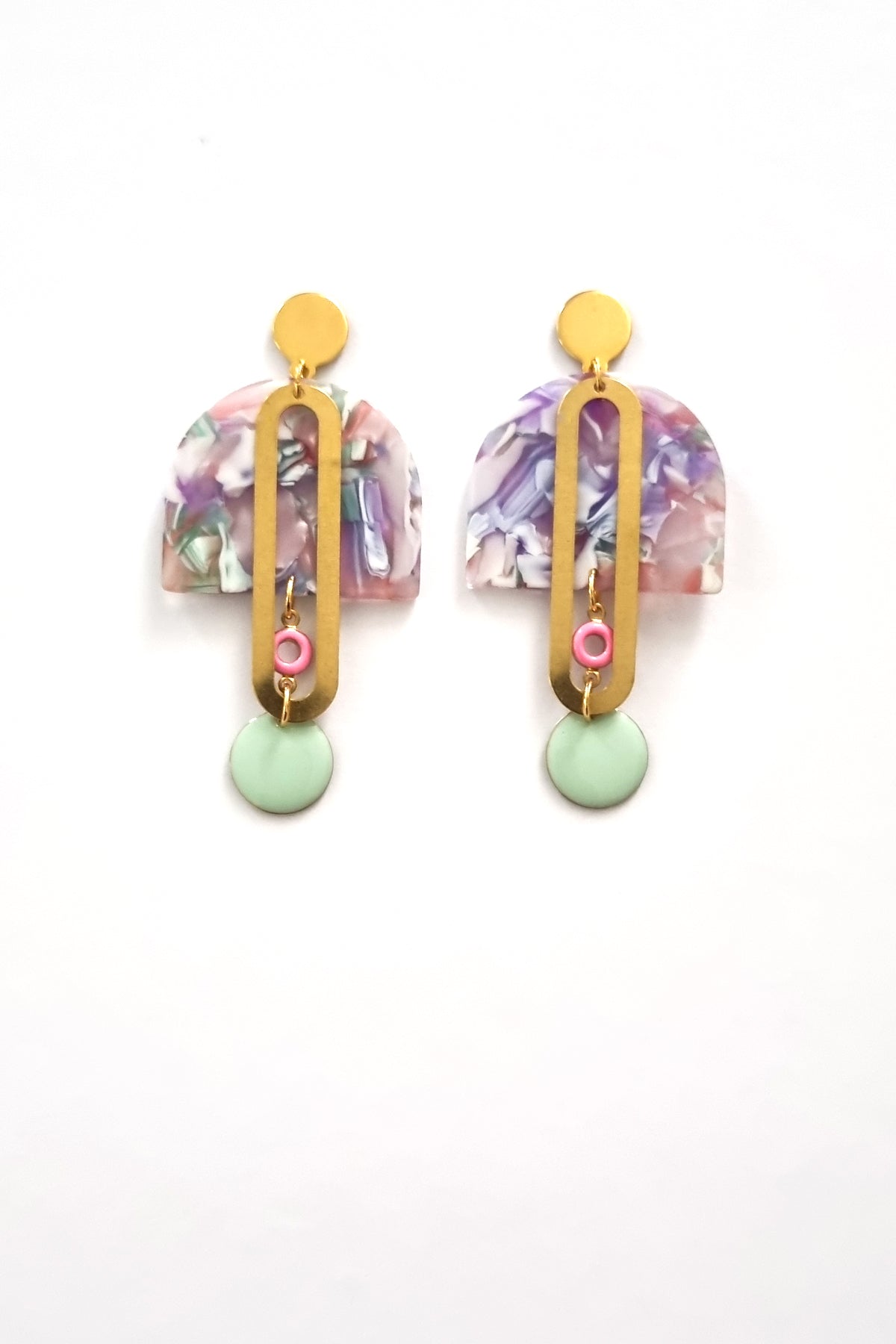 A pair of stud dangle earrings sits against a white background. They feature a mauve and mint multicoloured acrylic arch, an elongated oval brass piece with a small pink enamel connector attaching the acrylic piece to the brass, and at the bottom hangs a mint enamel dot.