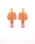 A pair of stud dangle earrings sits against a white background. They feature an orange and orchid multicoloured acrylic arch, an elongated oval brass piece with a small orange enamel connector attaching the acrylic piece to the brass, and at the bottom hangs an orchid enamel dot.
