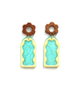 A pair of stud dangle earrings lay against a white background. They feature a wooden flower stud top followed by an aqua acrylic arch with a silver thread detail. On top sits an enamel wavy arch frame in yellow.