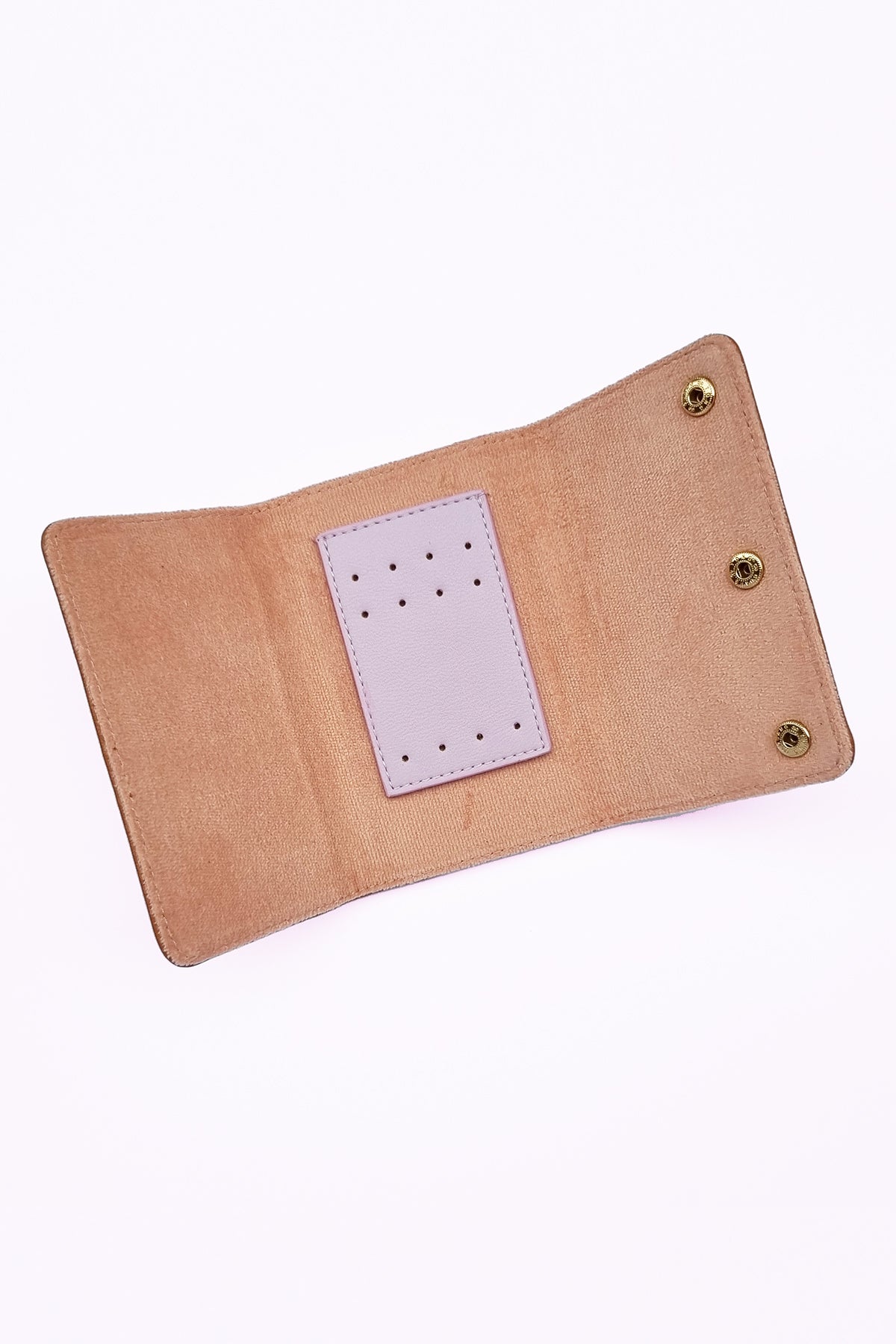 An open jewellery snug shows the inner features, a flocked pink fabric with a small rectangle of pu perforated with 8 holes up the top and four holes down the bottom. Three gold press stud buttons are shown down the right side of the snug.